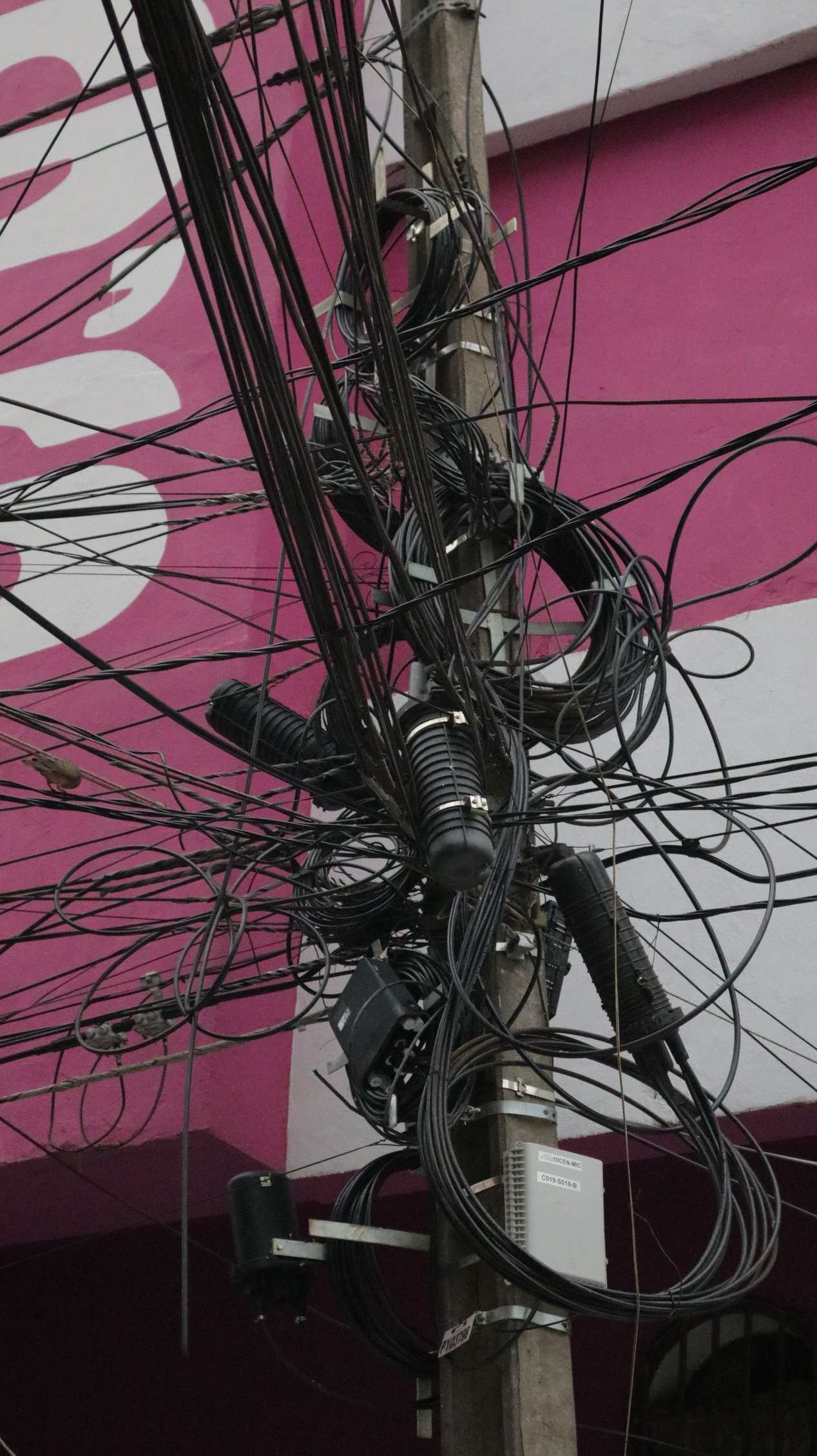 Complex network of tangled power cables on an urban electric pole