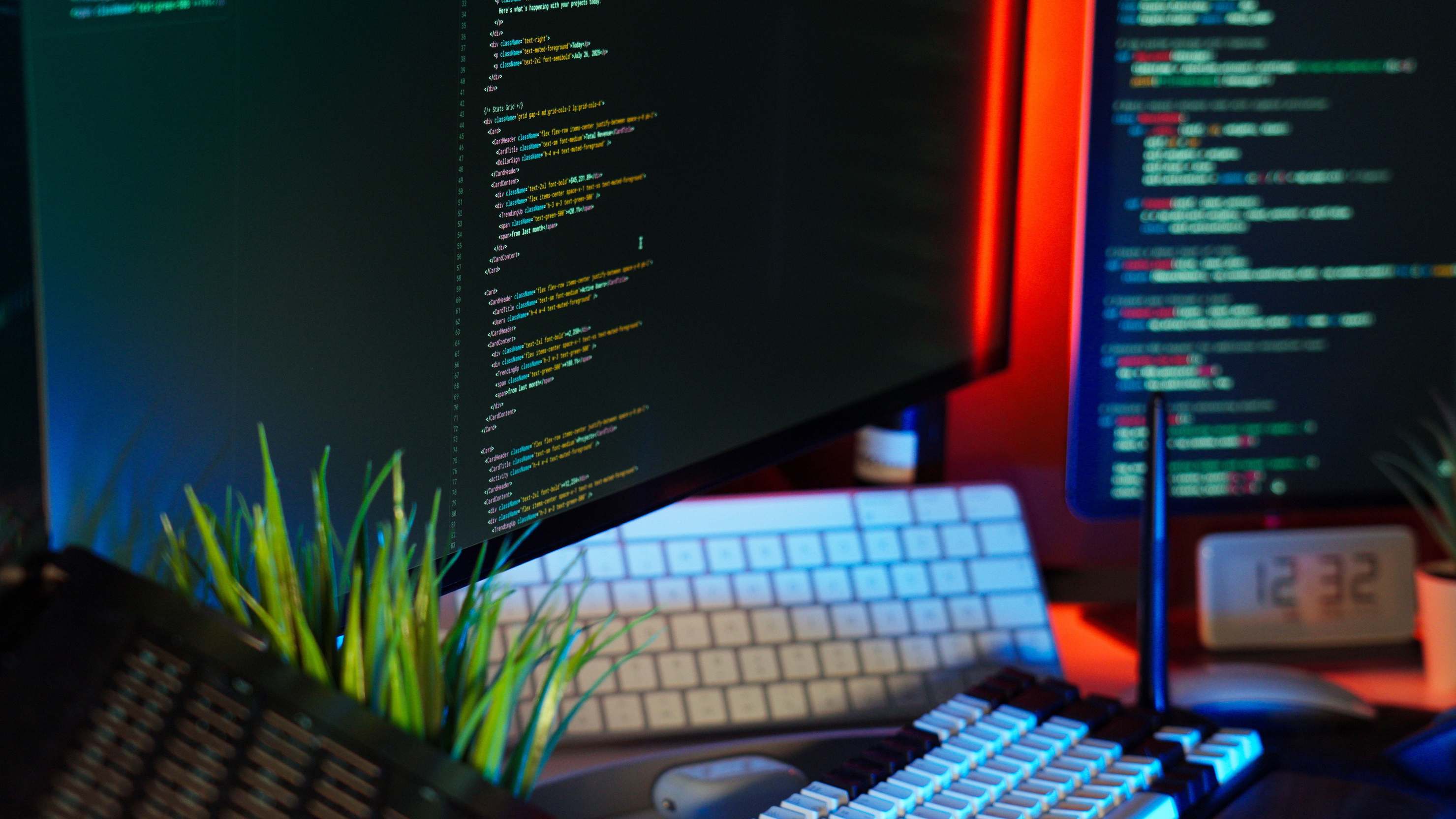 Laptop and peripherals on a desk used for software work with code on monitors